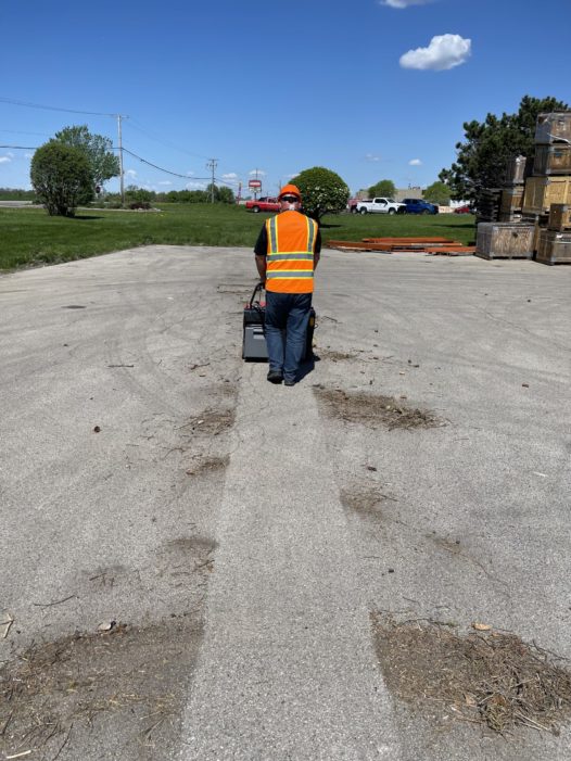 PowerBoss Collector 34 Walk-behind sweeper cleaning dirt in parking lot