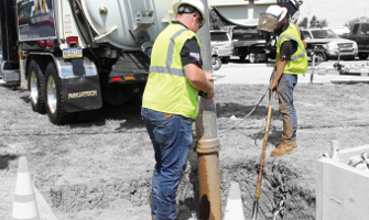 Workers shown daylighting a buried utility with a hydro excavator truck