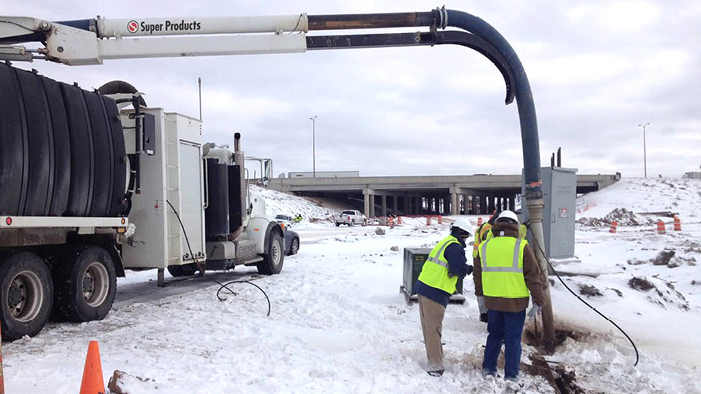 Using a hydro excavator to dig along a highway in the snow
